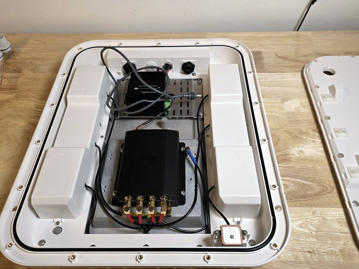 Inside the vehicle roof enclosure — Peplink router with cellular antenna connections and Starlink power feed