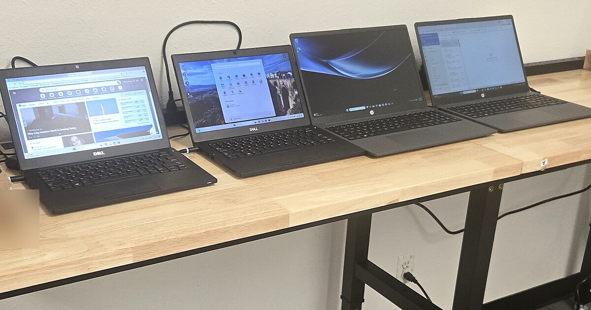 Business laptops being set up and evaluated on a work bench.